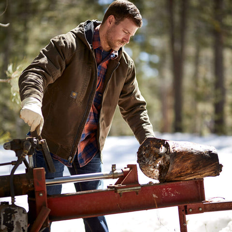 Man wearing Ariat men's Rebar Washed DuraCanvas Insulated Jacket in brown while operating a log splitter
