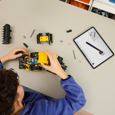 Boy assembling LEGO Technic Volvo L120 Electric Wheel Loader Construction Toy 42209