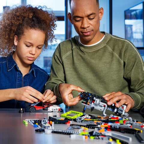 LEGO Technic PEUGEOT 9X8 24H Le Mans Hybrid Hypercar showing man and girl assembling it