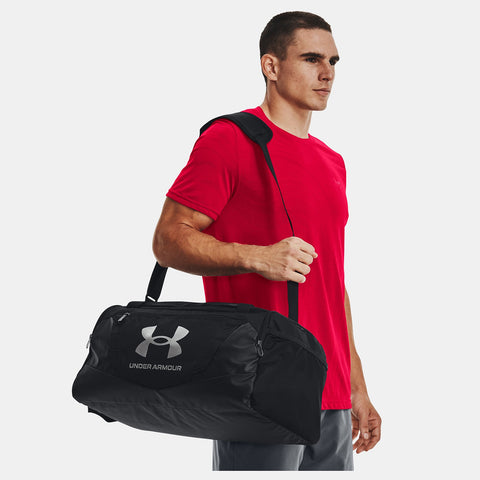 Man in red shirt carrying Under Armour Undeniable 5.0 black duffle bag on shoulder
