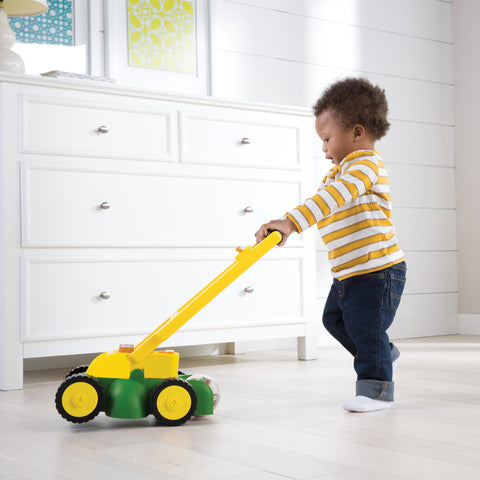 Child playing with toy John Deere mower