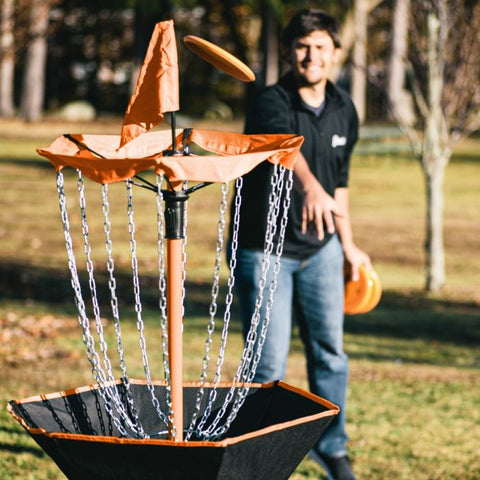 man throwing disc golf disc at target