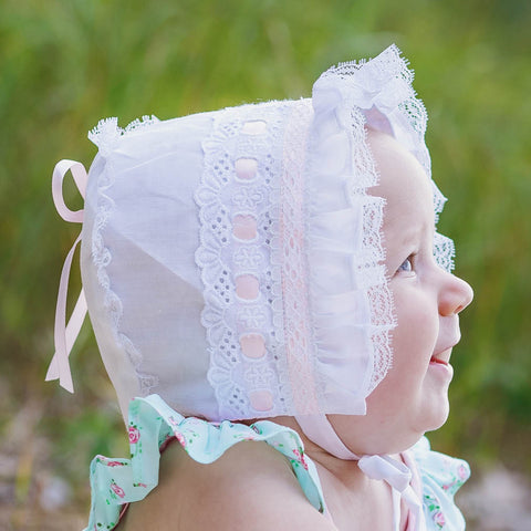 Baby wearing pink ribbon bonnet.