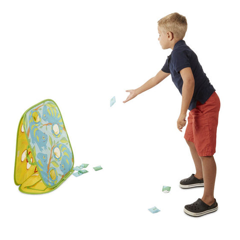 child tossing a bean bag towards the game