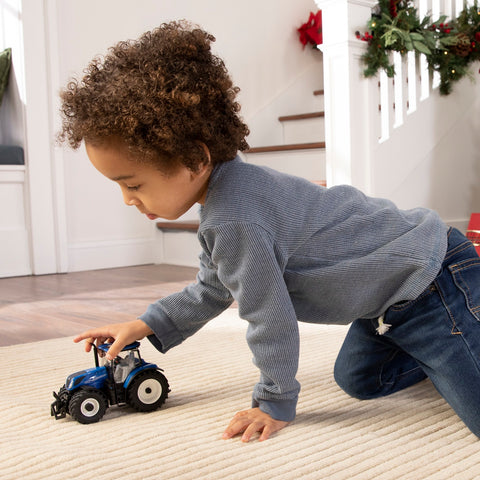 Boy playing with Ertl 1:32 scale New Holland T7.300 model tractor