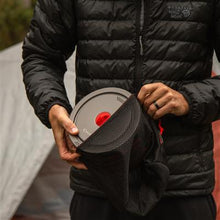 man putting cookware in mesh bag