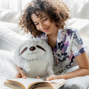 girl reading a book and snuggling with supersized sloth