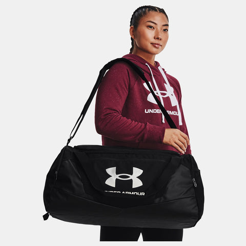 Woman carrying black Under Armour medium size Undeniable 5.0 Duffle Bag over shoulder