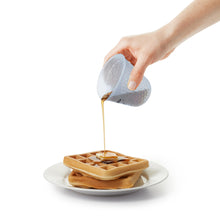 Pouring syrup over waffles.
