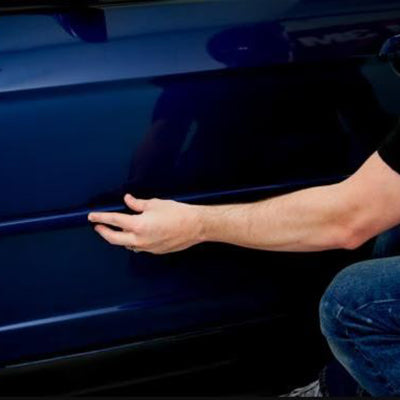 Man Adhering Trim to Vehicle