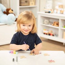 girl decorating wooden butterfly magnet