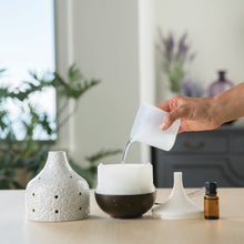 Adding water to essential oil diffuser.