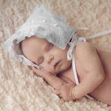 Baby sleeping wearing white ribbon baby bonnet.