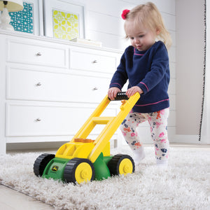 Child playing with lawn mower on carpet