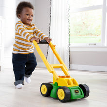Toddler boy pushing lawn mower