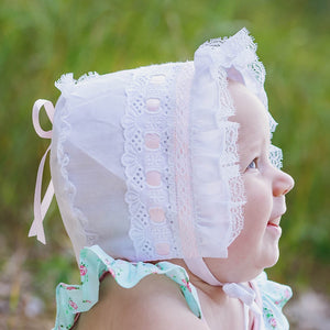 Baby wearing pink ribbon bonnet.